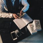 Businessman organizing finances with tech devices and cash on desk.